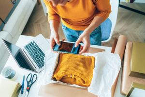 Re-Commerce Studie Ein Pullover wird zum Online-Weiterverkauf vorbereitet.